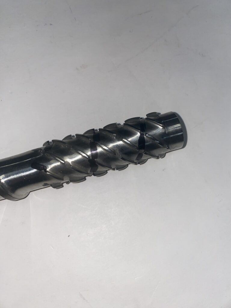 Close-up of a metal cutting tool with a spiral design, used for machining or shaping materials in industrial applications.