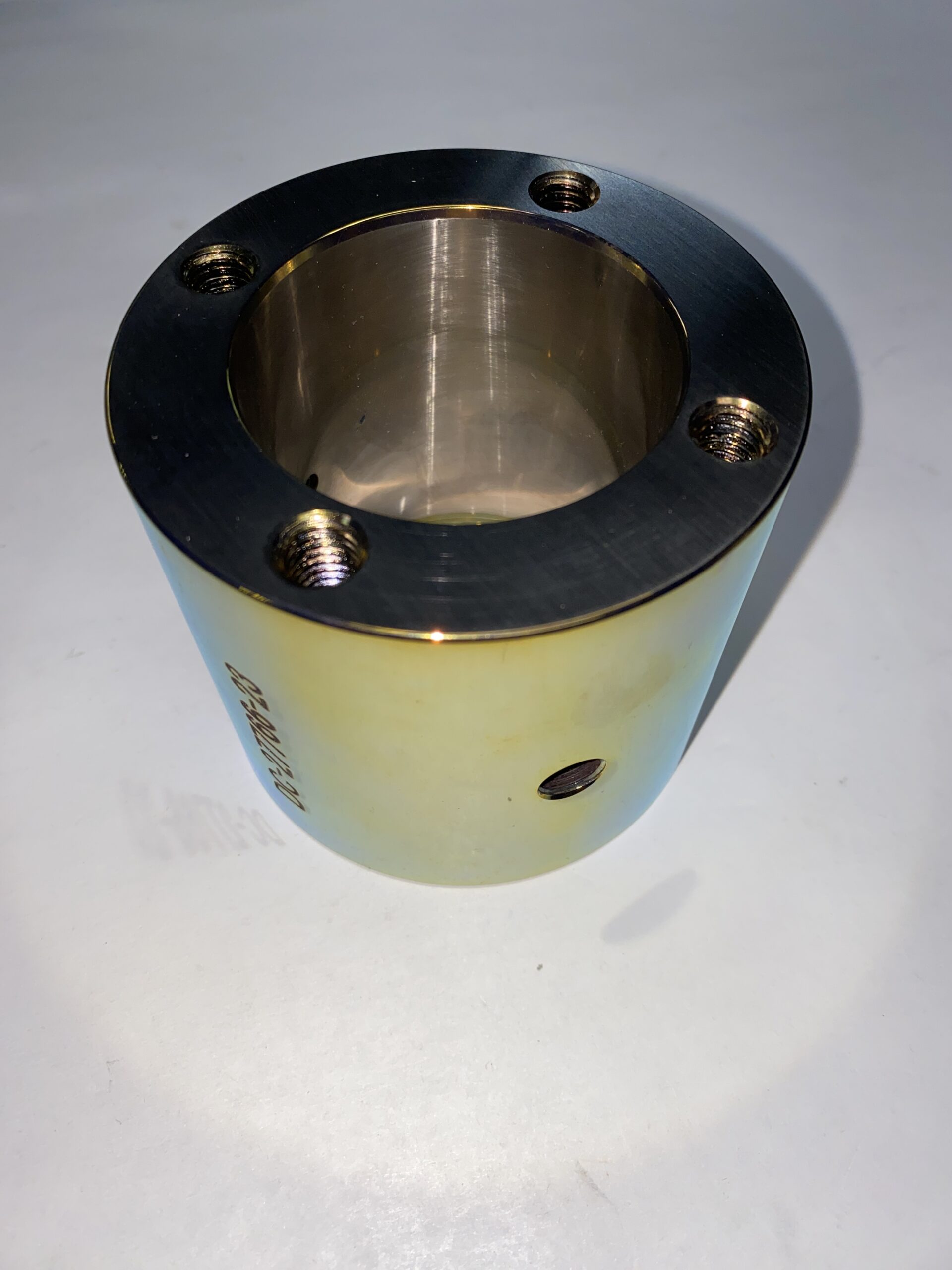 Metal cylindrical component featuring multiple threaded holes. It appears to be part of a mechanical assembly, relevant for engineering or manufacturing contexts.